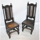 A pair of 18th century oak hall chairs with panel back shaped rails and barleytwist back supports,