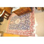 A Kashan rug with central medallion against blue ground within triple cream and red ground borders