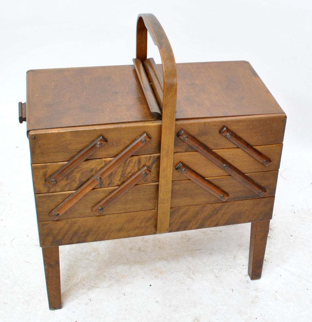 A 1940s sewing box with three hinged stepped drawers, on four square tapering legs, length 50cm.