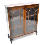 An early 20th century walnut two door glazed bookcase/display cabinet with two interior shelves,