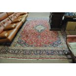 A good and large Kashan rug with central medallion against red ground within triple tone border of