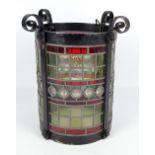 An early 20th century leaded and stained glass wrought iron framed cylindrical light fitting with