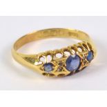 An 18ct yellow gold ring, set with three graduated sapphires (one replaced with glass), size Q,