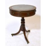 A reproduction mahogany drum table with inset leather top above three outswept legs to brass paw