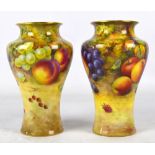 A pair of Royal Worcester baluster vases with flared gilt decorated rim, painted with fruit,