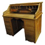 An early 20th century oak roll top desk with fitted interior above kneehole flanked by four short