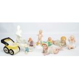 A group of bisque porcelain figures including babies and a ceramic model pram.