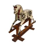 A rustic wooden rocking horse painted in dapple grey with amber glass eyes, 90.5cm.