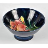 MOORCROFT; a small footed bowl with floral tubeline decoration on navy ground,