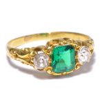 A Victorian yellow metal ring set with a princess cut emerald flanked by two round cut diamonds,