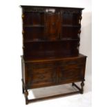 An early 20th century oak Jacobean style dresser with boarded plate rack centred with cupboard