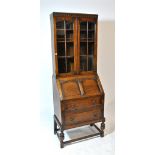 An early 20th century oak bureau bookcase with carved frieze above twin glazed doors enclosing