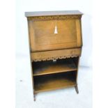 An early 20th century oak students bureau with fretwork carved frieze, sectioned interior,