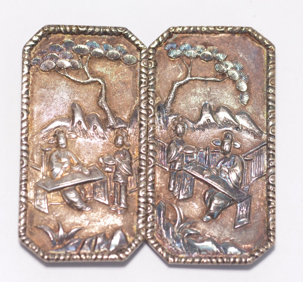 A Chinese export silver two piece belt buckle decorated with scenes of figures in a landscape,