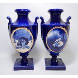 A pair of blue and white porcelain urns with scrolling handles and each set with a gilt heightened