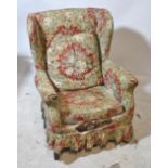 An Edwardian wing back armchair on square tapering supports.