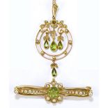 An Edwardian Art Nouveau yellow metal green peridot and cultured pearl pendant suspended on a fine