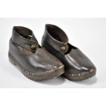 A pair of children's clogs with ankle straps and thick patterning to the leather wooden and metal