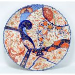 A large Japanese Meiji period Imari shaped circular charger with moulded body painted in underglaze