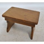 ALAN GRAINGER; an oak footstool with two shaped supports, width carved acorn signature, width 36cm.