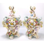 A pair of circa 1900 Sitzendorf porcelain urns and covers each decorated with a couple of cherubs