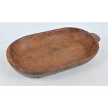 A rustic treen bowl with single moulded handle, length 56cm.
