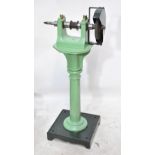 A pale green painted grinding wheel with turned central column and square sectioned base,