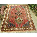 An Eastern rug, with three medallions in green and black on a red ground, three floral guard