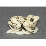 Asiatika. Netsuke. Material(?) Kleiner kniender Frosch auf einem Blatt. Kleine monochrome Figur mit