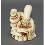 Asiatika. Netsuke. Elfenbein. Sitzende männliche Figur mit Kind. Kleine monochrome Figuren mit