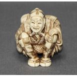 Asiatika. Netsuke. Elfenbein, etwas eingefärbt und verziert. Alter Reisender mit Rucksack auf dem