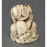 Asiatika. Netsuke. Elfenbein. Auf dem Kopf stehende Figur eines Mannes. Kleine monochrome Figuren