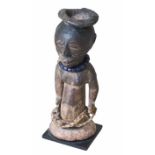 Fetisch-Figur der Kusu aus dunkel gefärbtem Holz mit Bast und Metall. Kongo, 1. Häfte des 20. Jhdts.