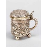 Small German silver tankard with lid and hand grip on three bowl feet, rich floral chased