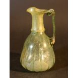 Small green glass jug with hand grip and extended waved border with spout; on the bowed body some