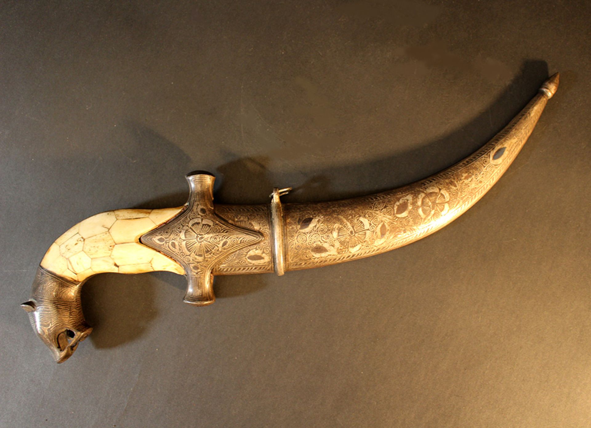 A Persian dagger, in S shape, with lion head grip end, bone grip and richly floral decorated