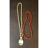 Lot of two necklaces: first with red corals and second with ivory with medaillion of a flower;