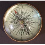 A paper weight compass with round glass dome and compass, inside with wind rose and grade meter;