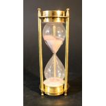 A hourglass with red sand in gilded bronze mantle with three collumns and compass on each end;