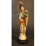 A Chinese sculpture of a lady with lotus blossom, standing on wooden base; gilded copper with rich