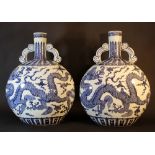 Two large Chinese pilgrim bottles; porcelain with long necks and each with two hand grips; round