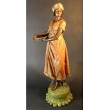 Ceramic sculpture of an Arabic girl holding a large plate, by a tree stump; on base;
