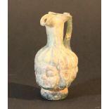 A Roman green glass mouth blown flask, decorated with a youth male head.11cm height