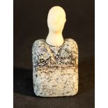 A small stone figure in sitting possition; green/black stone with geometrical grooves and white