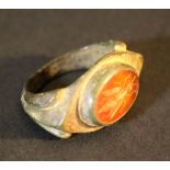 A bronze ring with a carnelian gemstone showing a bee; the bronze with verdigris and signs of age;