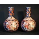 Pair of Imari porcelain vases with short necks, painted under glaze; each with two cartouches with