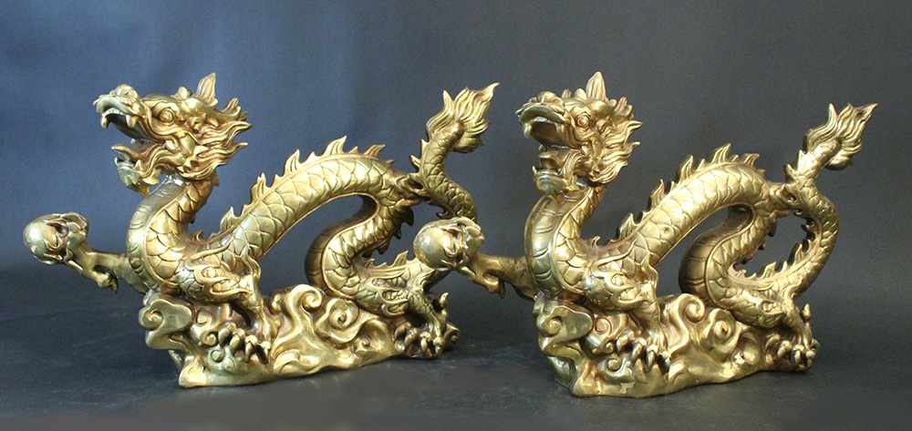 Pair of Chinese bronze gilded dragons, standing in a basis and stretching the right claw with a