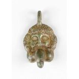 An erotic bronze amulet in ancient manner with a male's head and a phalus in his mouth; on top