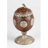 Coconut goblet with rich silver mounts and coins; on central extended foot with floral engraved