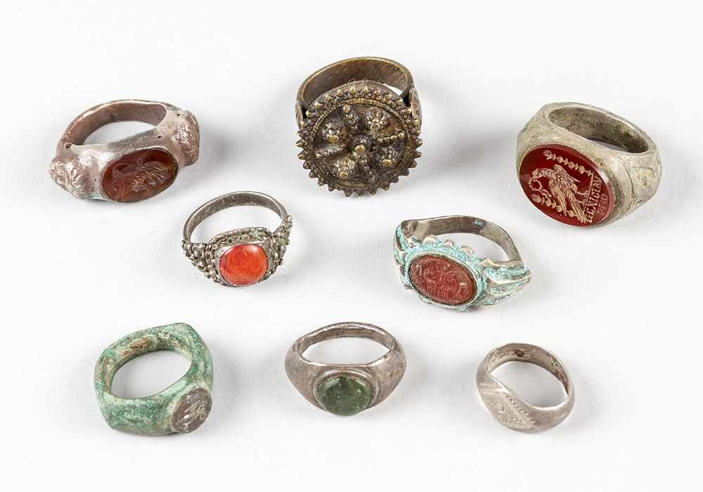 A collection of eight ancient and later rings, bronze and other materials, partly with red gemstones